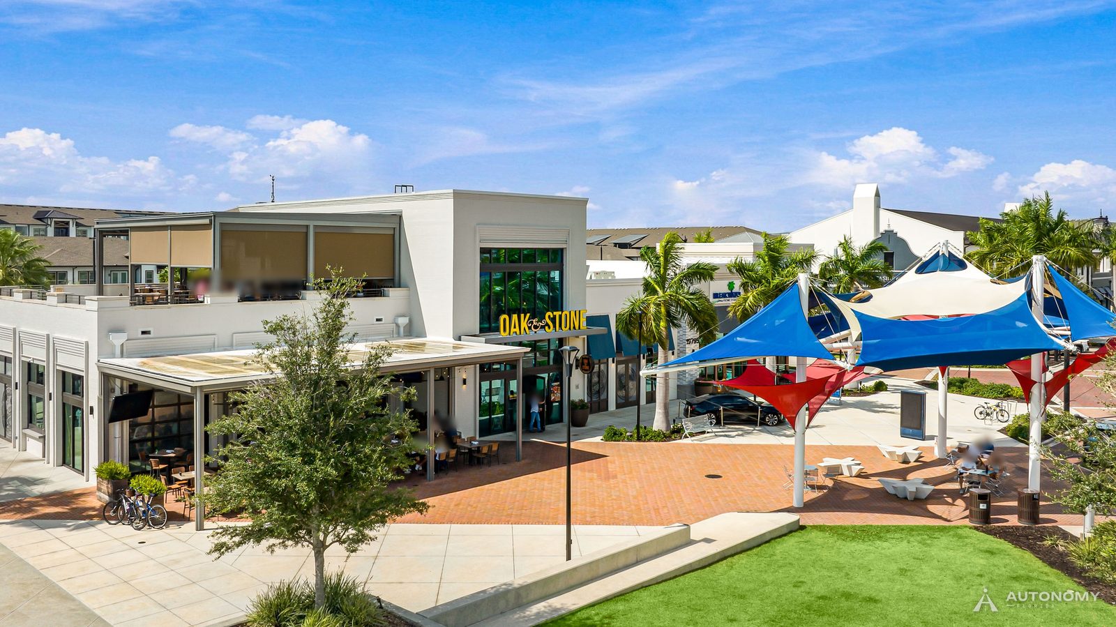 Downtown Wellen plaza with red, white and blue shade sails, a lawn and restaurant patios